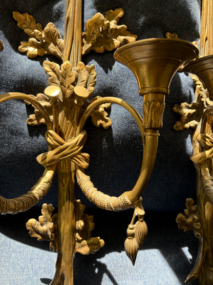 Stunning antique pair of French Louis XVI style brass wall sconces with bows, tassels, and horn motif designs!