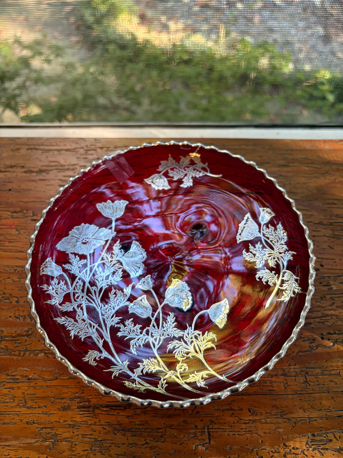 Beautiful red glass footed dish with silver florals and scalloped rim!