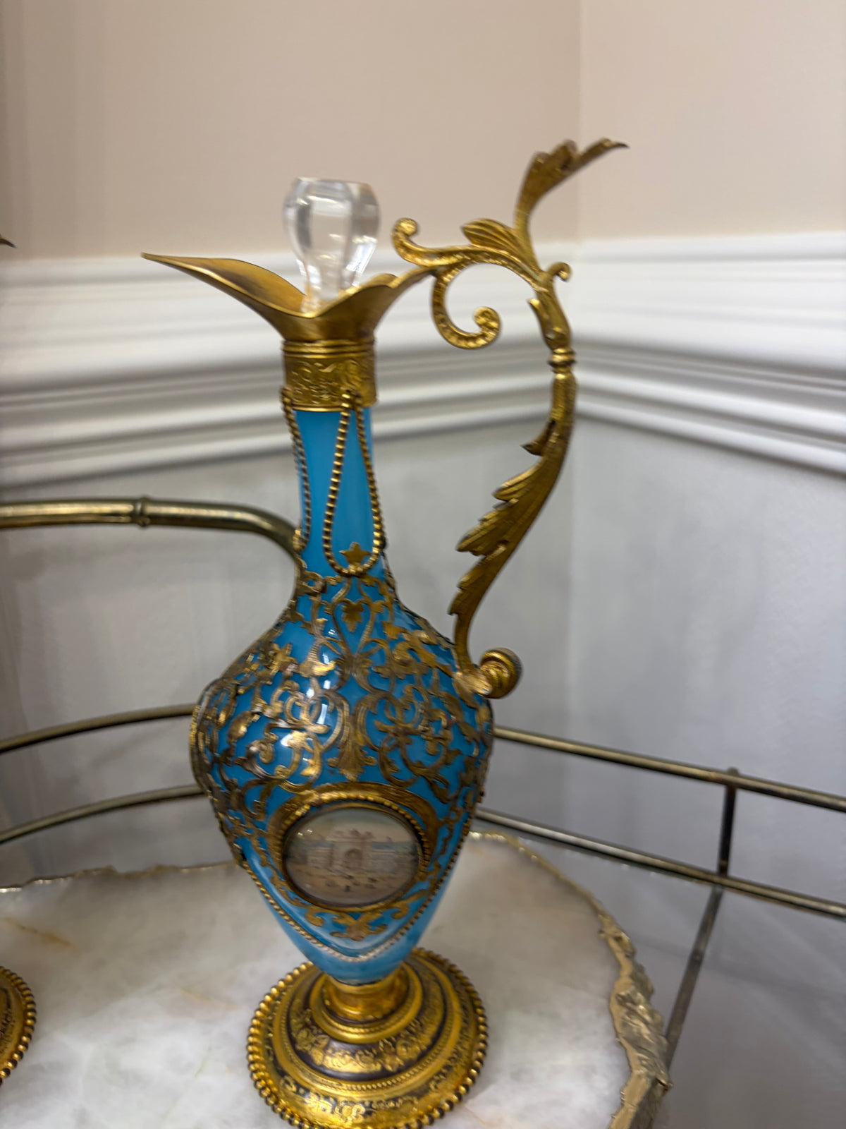 Stunning antique 19th-century French Napoleon III-style blue opaline glass ewer jugs pair adorned with elaborate gilt ormolu (gold-plated bronze) mounts, scrollwork, and scenic medallions! Circa 1836-1850