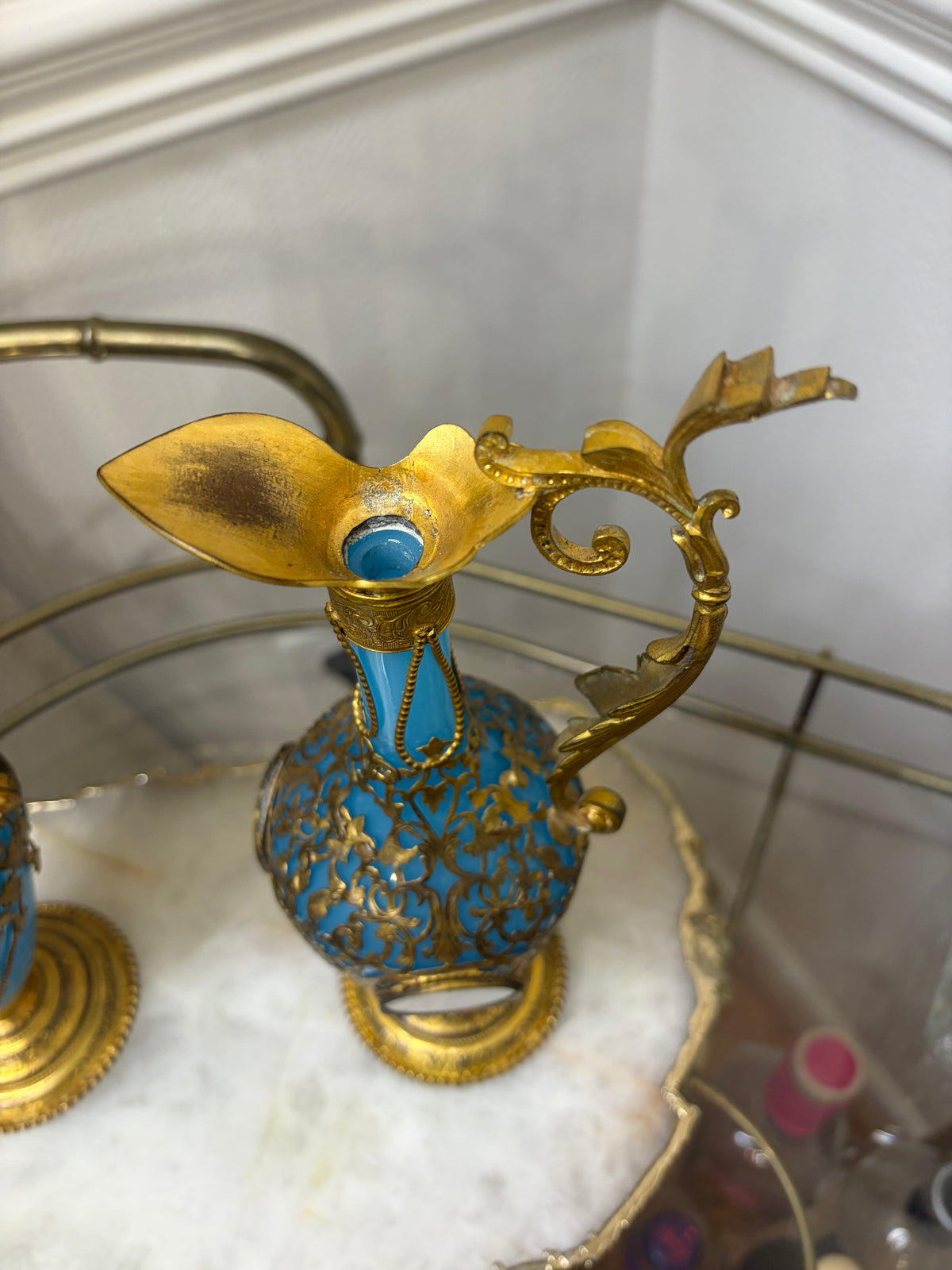 Stunning antique 19th-century French Napoleon III-style blue opaline glass ewer jugs pair adorned with elaborate gilt ormolu (gold-plated bronze) mounts, scrollwork, and scenic medallions! Circa 1836-1850