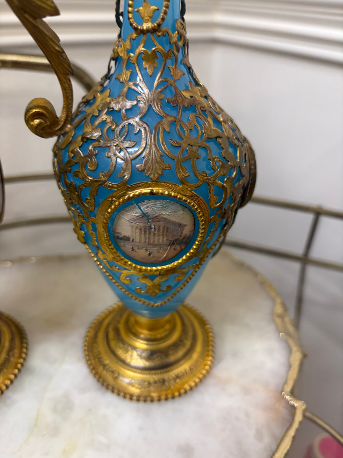 Stunning antique 19th-century French Napoleon III-style blue opaline glass ewer jugs pair adorned with elaborate gilt ormolu (gold-plated bronze) mounts, scrollwork, and scenic medallions! Circa 1836-1850