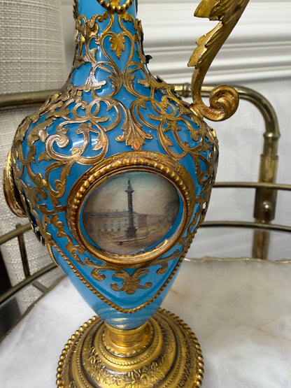 Stunning antique 19th-century French Napoleon III-style blue opaline glass ewer jugs pair adorned with elaborate gilt ormolu (gold-plated bronze) mounts, scrollwork, and scenic medallions! Circa 1836-1850